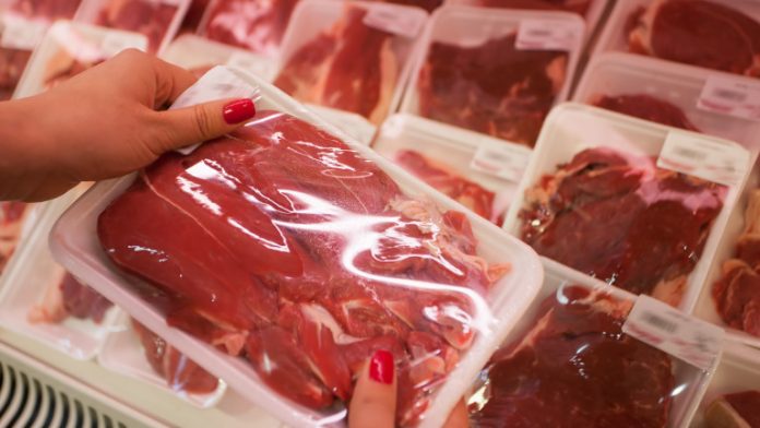 Packaged meat with woman hand in the supermarket